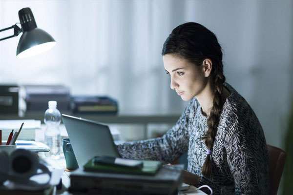 Mujer con suéter gris sentada utilizando una computadora